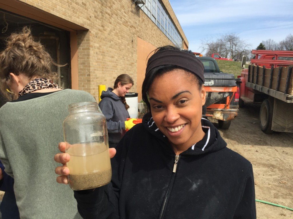 A student holds up a glass of dirty water, before we put it through the filter.