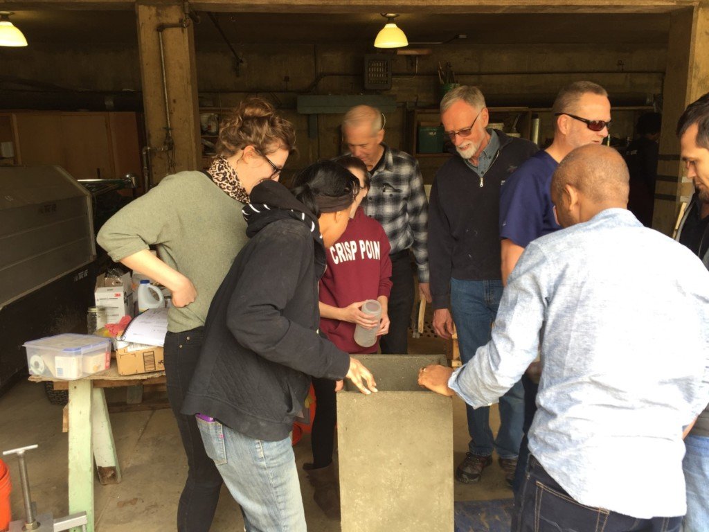 Students inspect the finished concrete biosand water filter after taking it out of the mold.